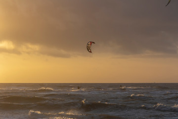 View of the north sea beach on a windy winter day at sunset, people, kitesurfing. Noordwijk, the Netherlands