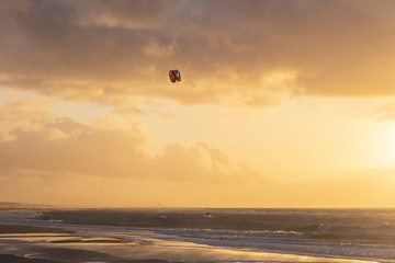 View of the north sea beach on a windy winter day at sunset, people, kitesurfing. Noordwijk, the Netherlands