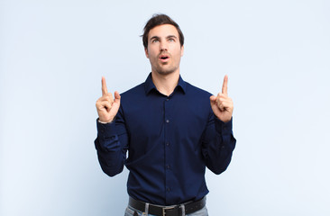  looking shocked, amazed and open mouthed, pointing upwards with both hands to copy space
