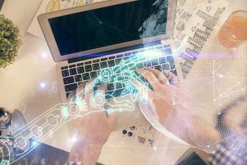 Double exposure of man's hands typing over computer keyboard and tech theme hologram drawing. Top view. Technology concept.