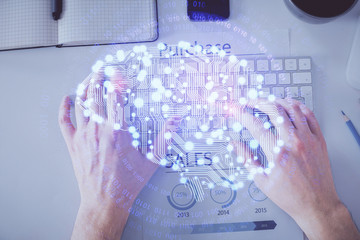 Double exposure of man's hands typing over computer keyboard and brain hologram drawing. Top view....
