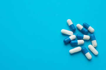 Antiviral capsules, pills for treatment on a blue background. White-blue capsules. Flat lay, top view
