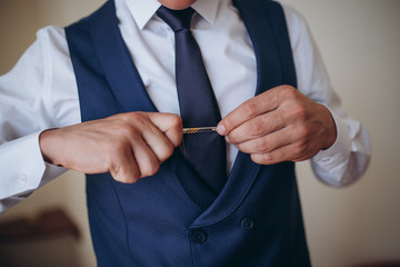 Grooms morning preparation, handsome groom getting dressed and preparing for the wedding, in dark...