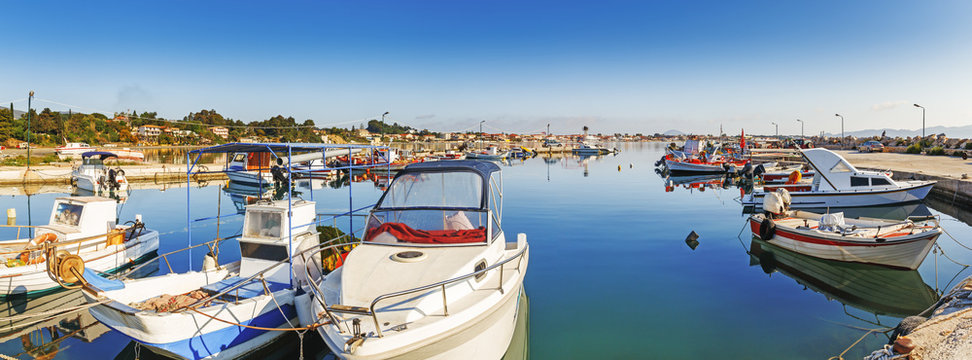 Banner of sea boat harbor at Zante Zakynthos Island in Mediterranean sea, in Greece. Peaceful morning scene in cozy island bay with anchored fishermen's vessels, panoramic view.