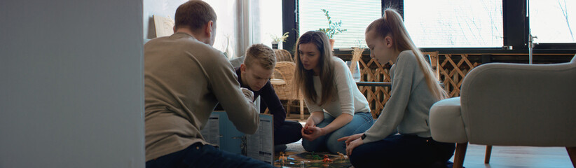 Family - father, mother and two kids playing a board game together. Stay home, quarantine. Board...