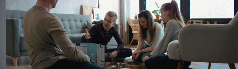 Family - father, mother and two kids playing a board game together. Stay home, quarantine. Board...