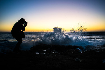 A wave breaks on the rocks, the photographer catches the moment