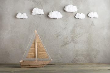 Travel and adventure creative concept - toy wooden boat, cotton sky on the background