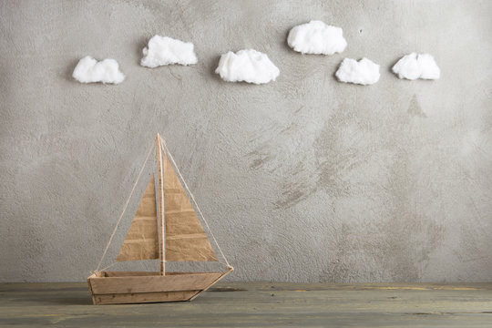 Travel and adventure creative concept - toy wooden boat, cotton sky on the background