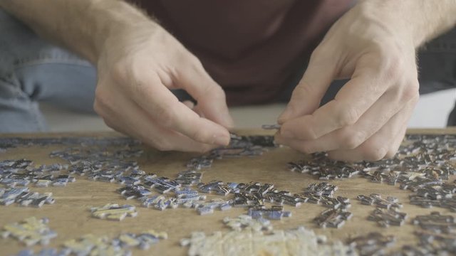 A guy doing a jigsaw puzzle. hands close up