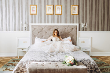 An incredibly bride sits on a bed in her bedroom. Bride morning.