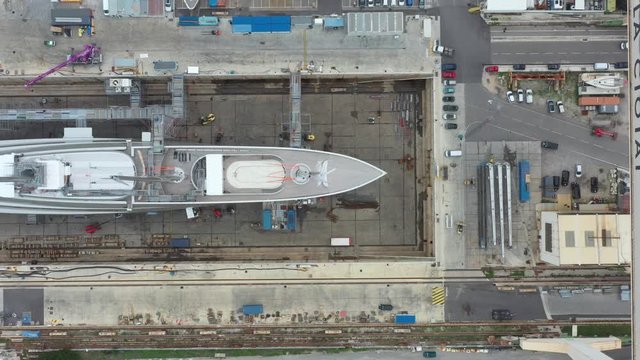 Aerial view of sea dry dock in La Ciotat city, France, the cargo crane, boats on repair, a luxury sail yacht and motor yacht, mountain is on background, shipyard