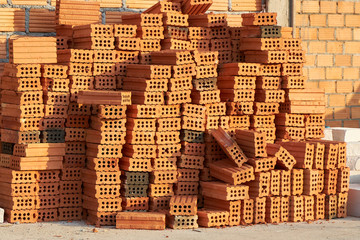 Red brick neatly stacked in rows for the construction of a residential building.