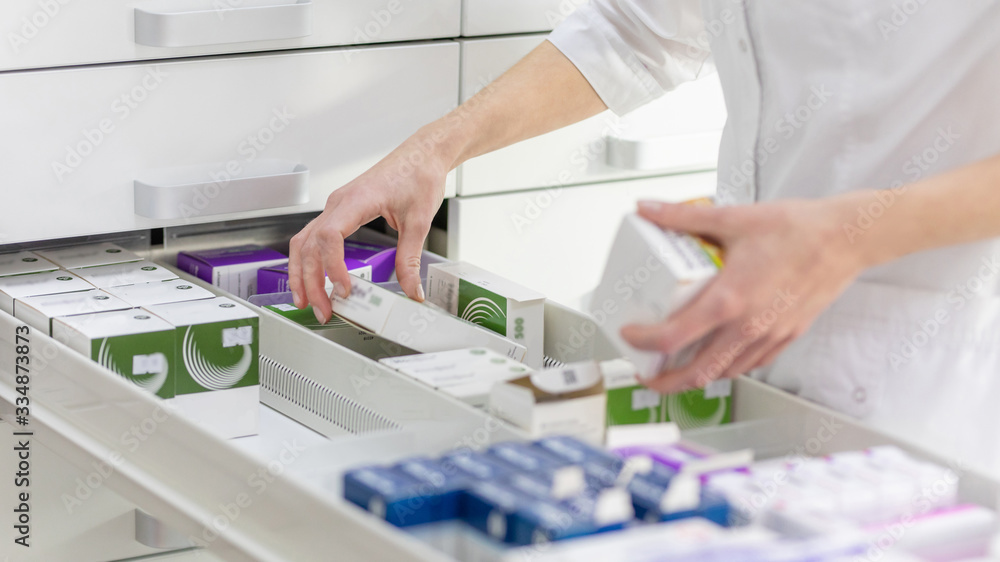 Wall mural pharmacist holding medicine box and capsule pack in pharmacy drugstore.