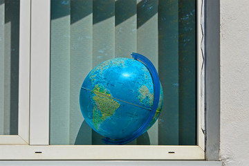 globe in the window with white jalousie aka blinds, school education diversity