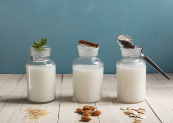 various types of plant-based lactose-free milk in glass bottles on a blue background, horizontally