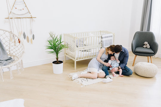 Beautiful caucasian family of mother, father and their baby of the floor the nursery