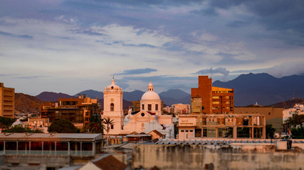 Fototapeta na wymiar Amazing view of the city of Santa Marta, Colombia. Colonial city with church view during the sunset, warm colors, beautiful sky and mountains.