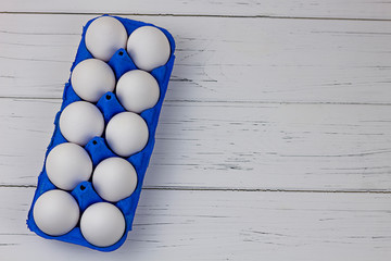ten white eggs in blue uniform on a wooden light background