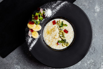 Oatmeal with berries, fruits and marmalade on vintage teal table top view in flat lay style. Hot and healthy breakfast and diet food.