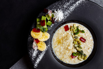 Oatmeal with berries, fruits and marmalade on vintage teal table top view in flat lay style. Hot and healthy breakfast and diet food.