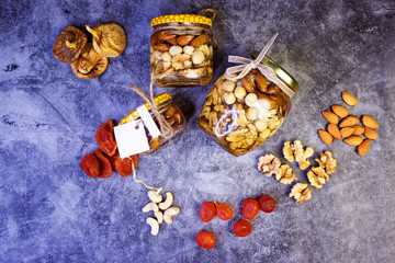 Fototapeta na wymiar Homemade granola from mix of cereals barley, oat, rye, bran with dry fruits, nuts and seeds in a vintage jar on a grey slate or concrete table- concept of healthy breakfast.
