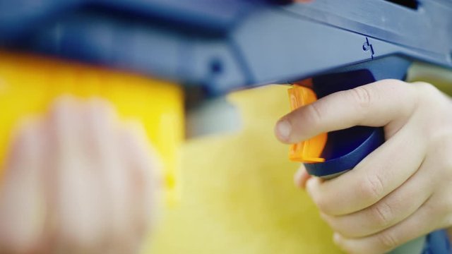 Close on young boy's finger as he pulls trigger on large colorful toy gun