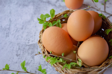 chicken eggs in a basket with green leaves. Easter composition