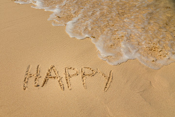 The word Happy written in the sand on a beach