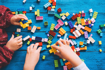 Children play and build with colorful toy bricks, plastic blocks.