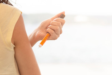 a girl inject insulin her arm at outdoor - obrazy, fototapety, plakaty