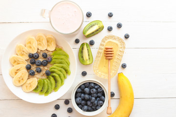 Oatmeal, granola with bananas, kiwi fruits, blueberries, honey and yogurt.Tasty  vegetarian breakfast. Healthy food or diet concept.  top view. Flat lay. Copy space.
