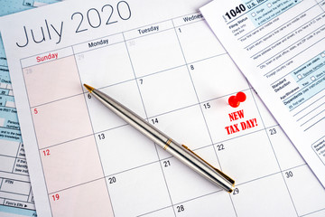 Postponed tax return deadline day to wednesday 15 july 2020 due to the covid-19 corona virus crisis. Day pinned with red pin, 1040 tax forms on the sides and pen on form. Taxes and financial.
