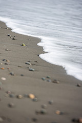 Beach with small pebbles, white foamy waves