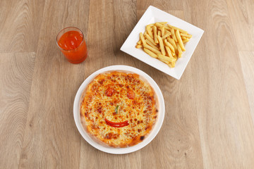 kids meal pizza - fries . juice . Margherita pizza with vegetables on a wooden background