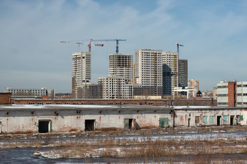 Fototapeta na wymiar Construction of a residential complex in Moscow with an old abandoned warehouse in the foreground