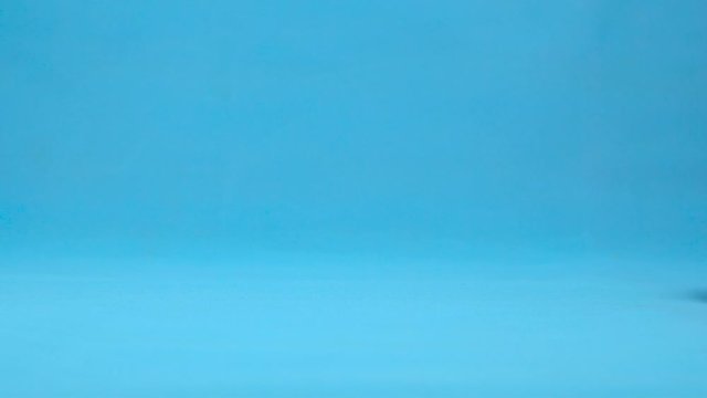 Orange with eyes rolls slowly. Orange with rolls on a blue background. Slow motion.