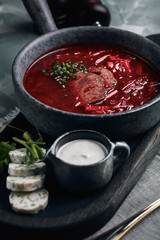Hot soup. Borsch with red beans and braised beef. Comfortable food. Serving with brown bread and pork fat in a rustic style.