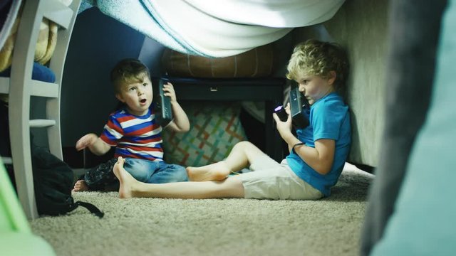 Two Boys Play With Flashlights And Walkie Talkies Inside Homemade Blanket Fort