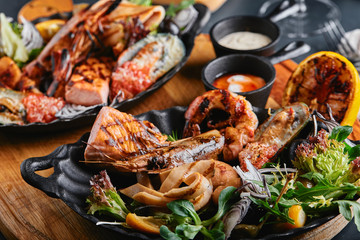 Assorted seafood on plates. Beautiful composition on a served seafood table, squid, shrimp, salmon steak and octopus. Food photo, low key, traditional Italian cuisine. Top view, save the space