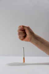 Person crushing a tobacco with his hand on a white background. Tobacco rejection concept. World tobacco day concept. Destroying a tobacco with hands to create awareness among people to stop smoking.