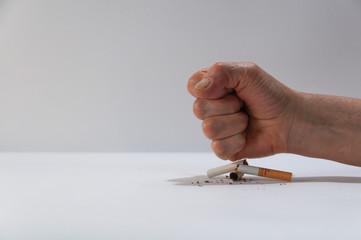 Person crushing a tobacco with his hand on a white background. Tobacco rejection concept. World tobacco day concept. Destroying a tobacco with hands to create awareness among people to stop smoking.