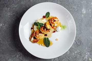Cheesecake, fresh jam and mint. Cottage cheese pancakes or curd fritters decorated powdered sugar in plate close view. Healthy and diet breakfast.