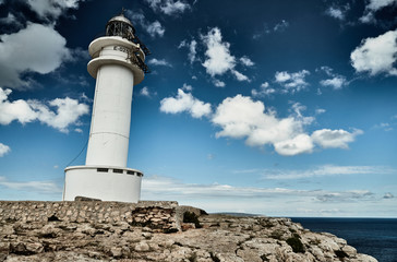 Fototapeta na wymiar Lighthouse on the Formentera island, Spain, the blue sky with white clouds, without people, rocks, stones, sunny weather
