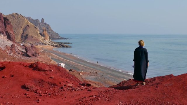Woman standing on top of a stunning scenic viewpoint to the sea on the red soil