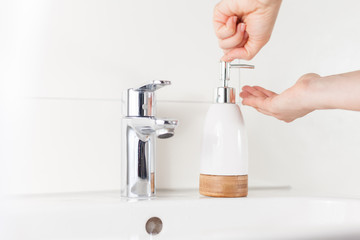 Woman hands using liquid soap dispenser in bathroom. Clean hands hygiene prevention of coronavirus virus outbreak. Covid19 hygiene concept. 