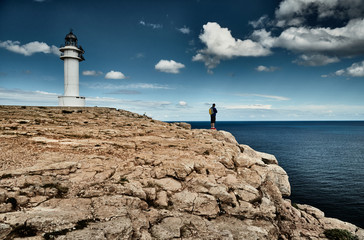 Lighthouse on the Formentera island, Spain, the blue sky with white clouds, The person with a bag...