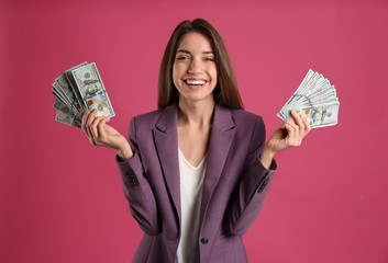 Happy young woman with cash money on pink background