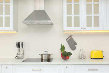 Pot on stove and fresh vegetables in modern kitchen