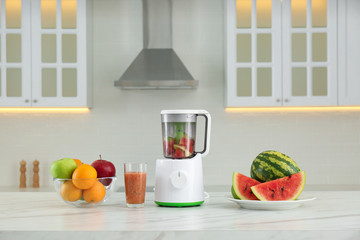 Blender and smoothie ingredients on table in kitchen
